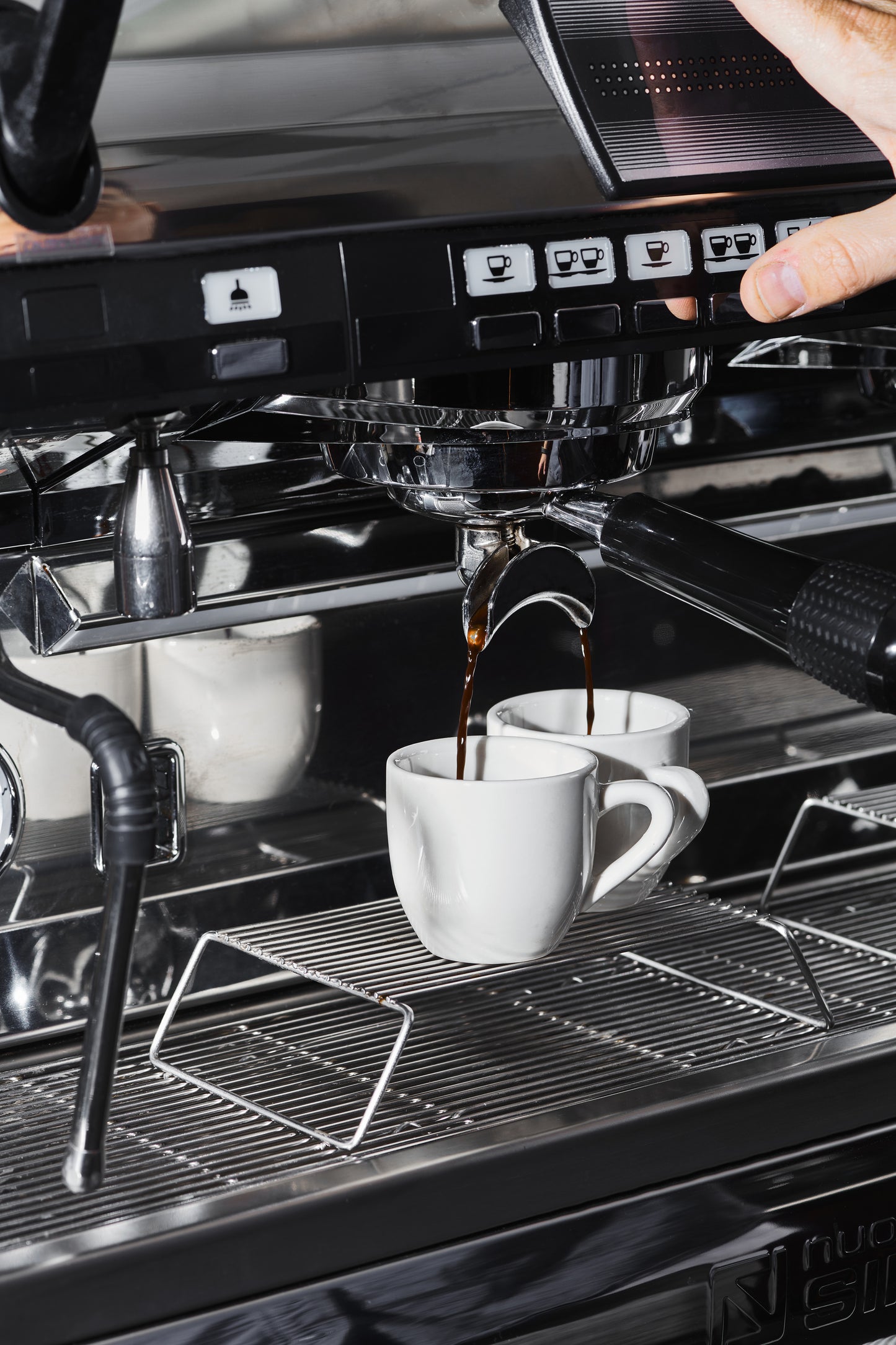a double shot of espresso being pulled into two white cups.