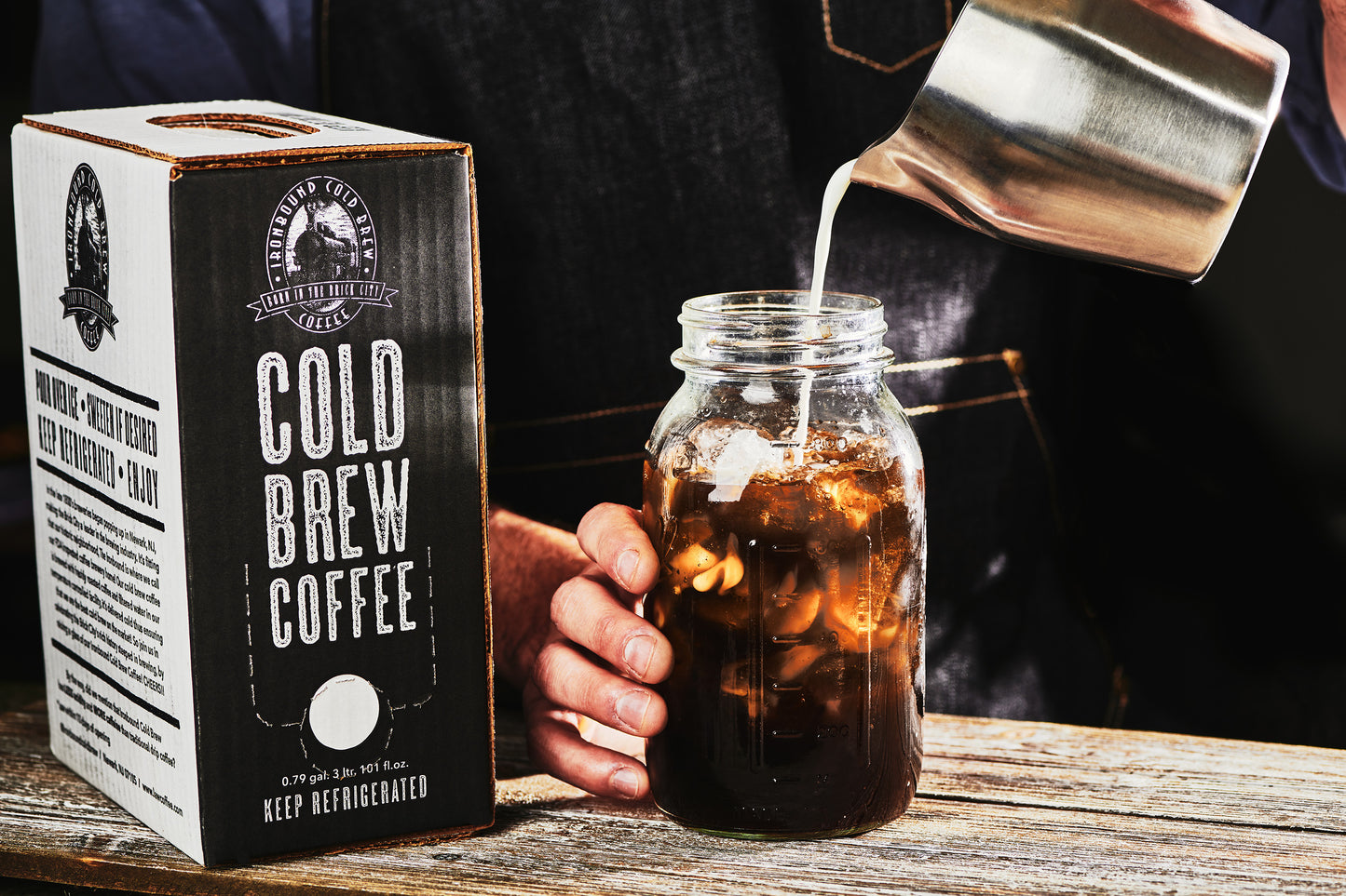 Barista pouring milk into a mason jar of Ironbound cold brew coffee