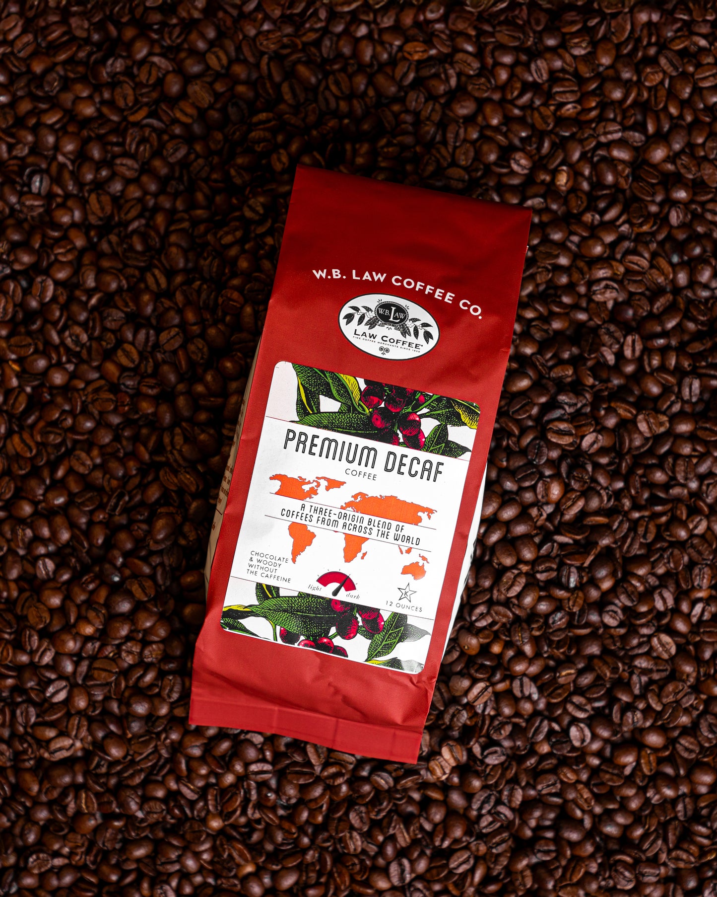 A 12oz bag of premium decaf coffee beans from W.B. Law Coffee Co. placed on a background of whole coffee beans.