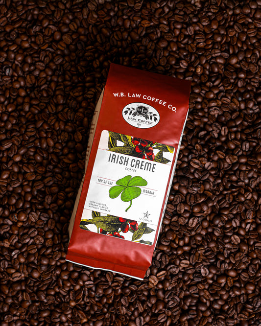 A 12oz bag of W. B. Law Coffee Co. Irish Creme coffee on top of a background of coffee beans.