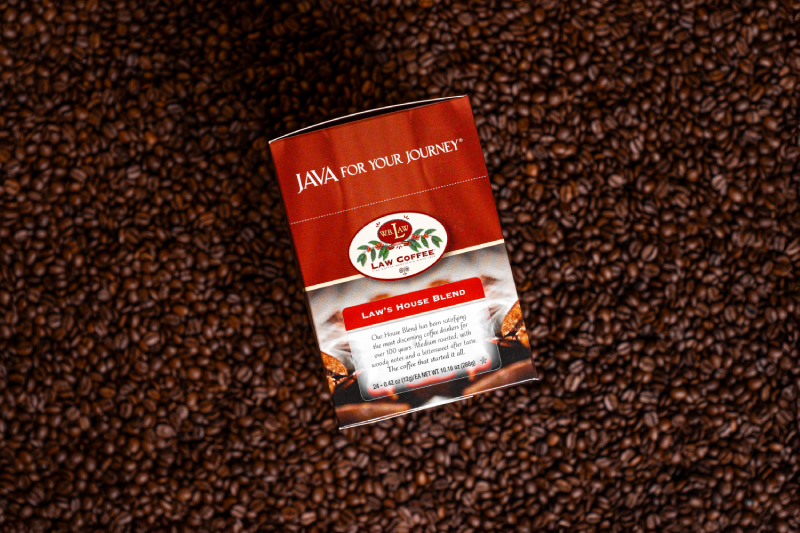 WB Law Coffee House Blend Single Serve Box sitting on a bed of coffee beans. 