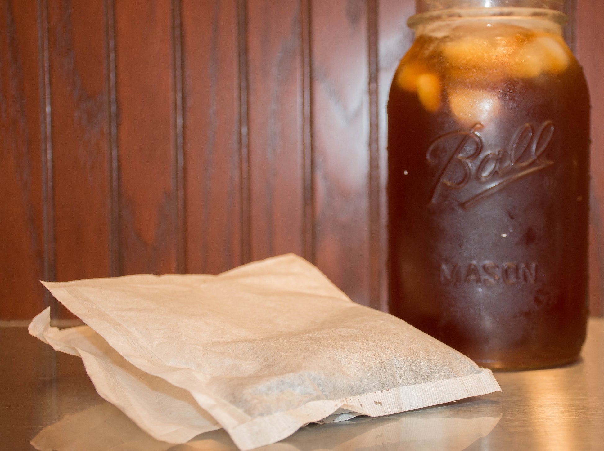 Iced tea filter bags sitting next to a mason jar of iced tea. 