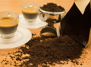 A pile of ground Cafe Mendez Espresso sitting next to a portafilter and two shots of espresso.